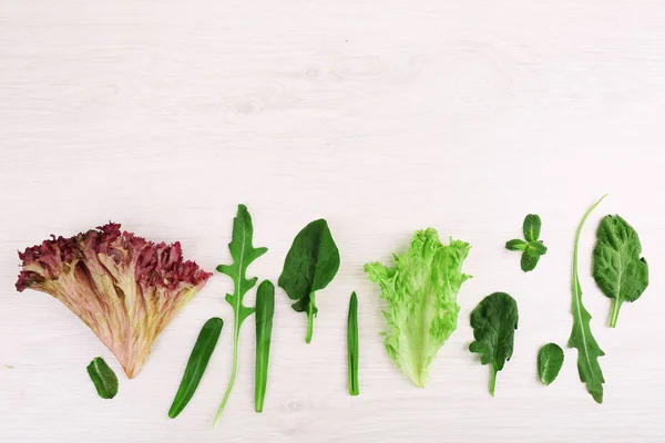 Scala aan groene bladeren voor salades, op houten tafel — Stockfoto