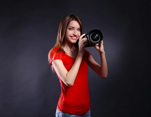 Joven fotógrafa tomando fotos sobre fondo negro — Foto de Stock