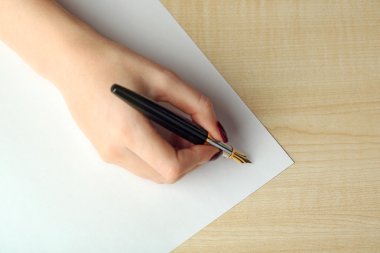 Tarafından dolma kalem ahşap masa arka plan üzerinde beyaz kağıda mektup yazma el