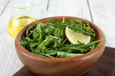 Yeşil salata ve ahşap masa, closeup dilimlenmiş limon kase
