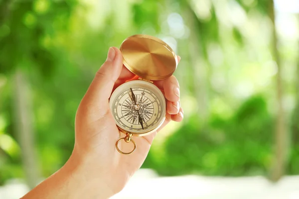 Human hand with compass on nature background — Stock Photo, Image