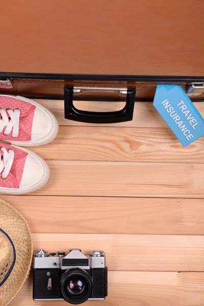 Maleta y cosas turísticas con seguro de viaje de inscripción sobre fondo de madera vista superior — Foto de Stock