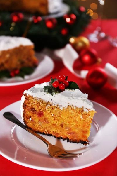 Кусок торта на тарелке с вилкой на столе с рождественским оформлением фона — стоковое фото