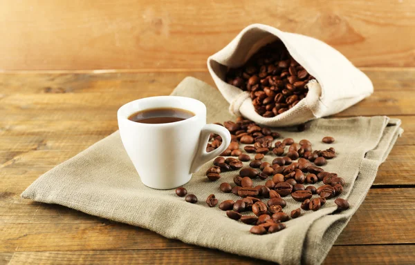 Kopje koffie met bonen op rustieke houten achtergrond — Stockfoto