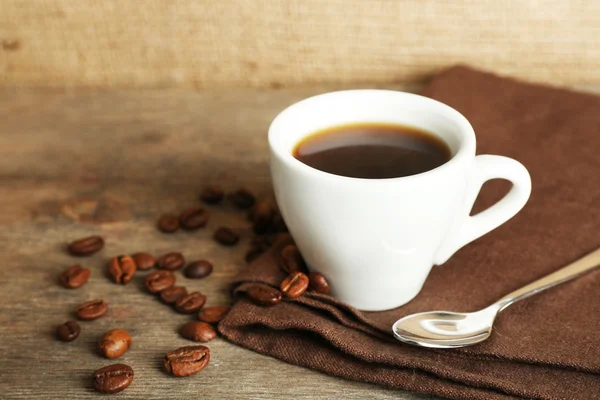 Šálek kávy s fazolemi na rustikální dřevěné pozadí — Stock fotografie