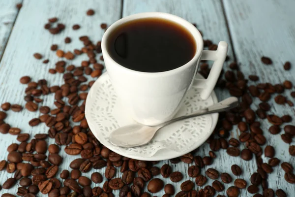 Tasse Kaffee mit Bohnen auf rustikalem Holzhintergrund — Stockfoto