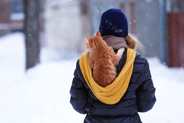 Woman with red cat on her back with snowfall background — Stock Photo, Image