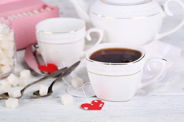 Tazza da tè a forma di cuore tag, scatola e teiera su sfondo di legno — Foto Stock