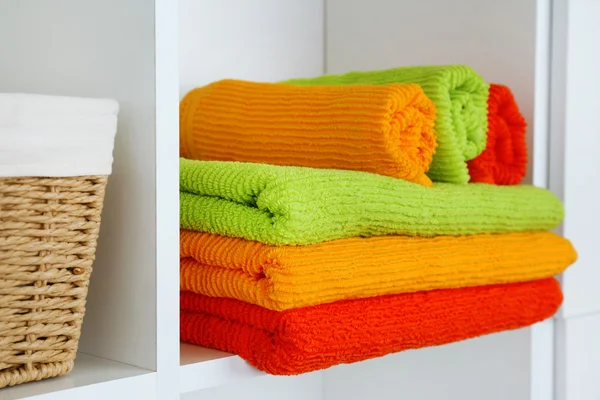 Kolorowe ręczniki z wiklinowym koszu na półce w szafie tła — Zdjęcie stockowe