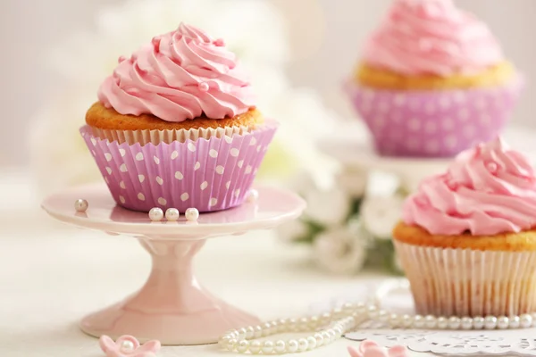 Deliciosos cupcakes en la mesa sobre fondo claro —  Fotos de Stock