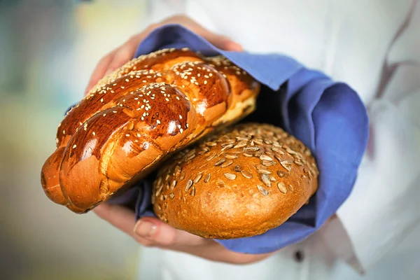 Fång av nybakade bröd i kvinnliga händer på ljus suddig bakgrund — Stockfoto