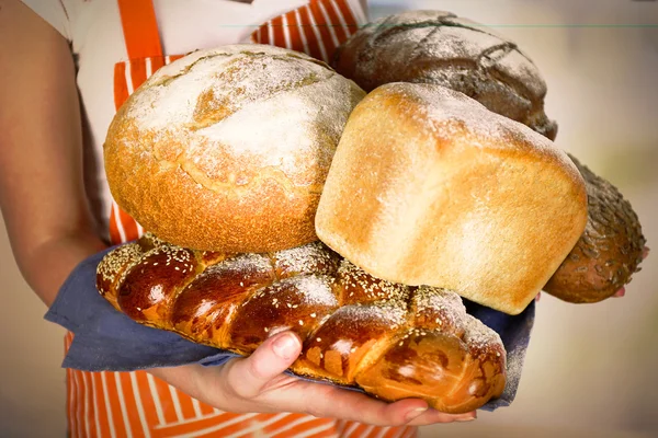 Armful of freshly bread in female hands on light blurred background — Stock Photo, Image