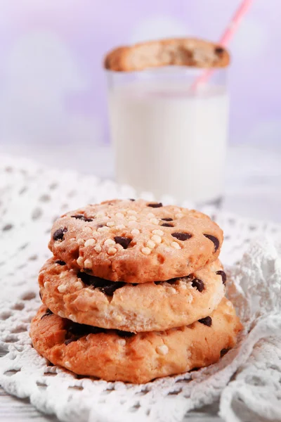 Biscoitos saborosos e vidro de leite na mesa de madeira a cores, no fundo brilhante — Fotografia de Stock