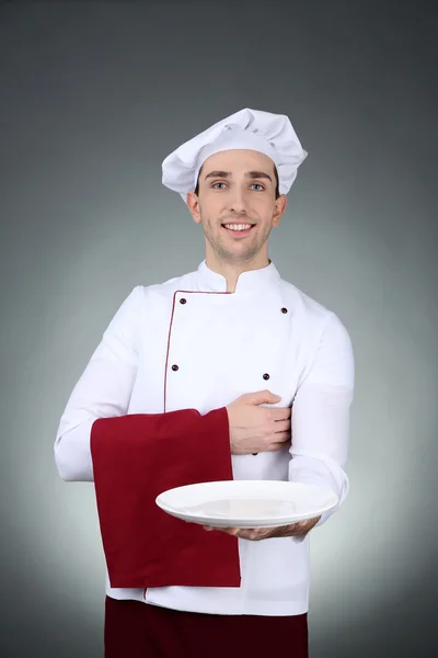Koch mit Handtuch auf der Hand und Teller auf dunklem Hintergrund — Stockfoto
