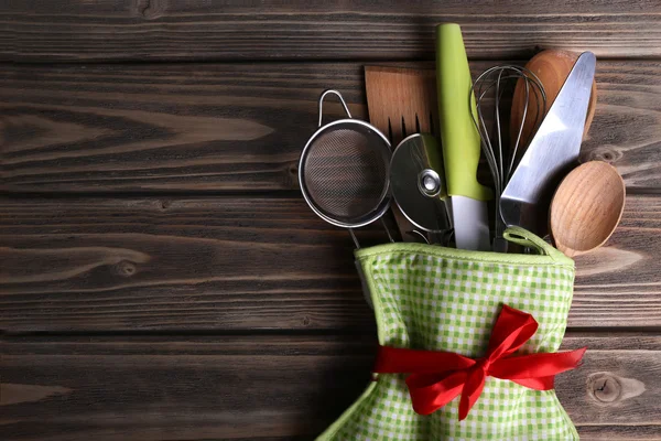 Set of kitchen utensils in mitten on wooden planks background — Stock Photo, Image