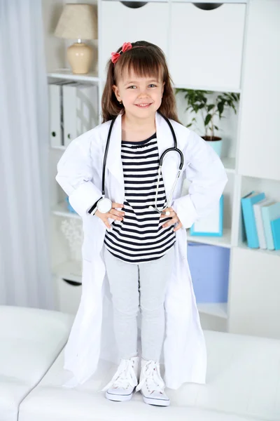 Liten flicka i läkare kostym med stetoskop på office interiör bakgrund — Stockfoto
