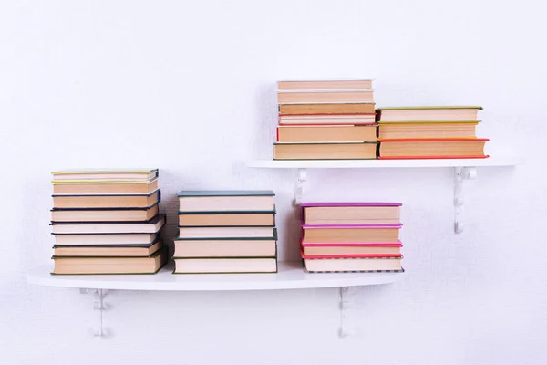 Livros em prateleiras no fundo da parede branca — Fotografia de Stock