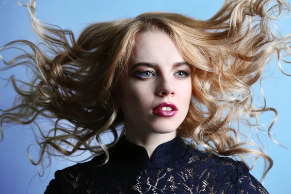 Retrato de una hermosa mujer joven en vestido negro sobre fondo azul claro —  Fotos de Stock