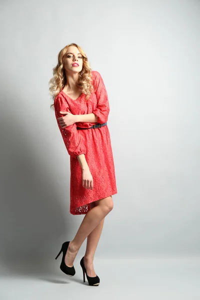 Mooie jonge vrouw in jurk van de kleur die zich voordeed op lichte achtergrond — Stockfoto