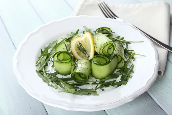 Teller mit grünem Salat mit Gurke, Rucola und Rosmarin auf Holztisch, Nahaufnahme — Stockfoto