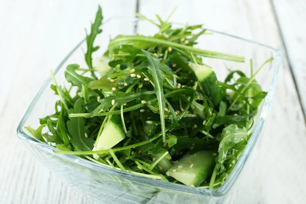 Glass bowl of green salad on wooden table, closeup — Stock Photo, Image
