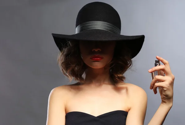 Hermosa mujer con frasco de perfume sobre fondo gris —  Fotos de Stock