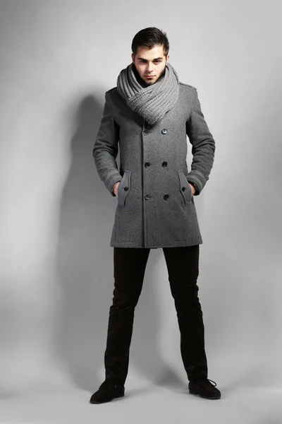 Молодий чоловік в пальто на сірому фоні — стокове фото