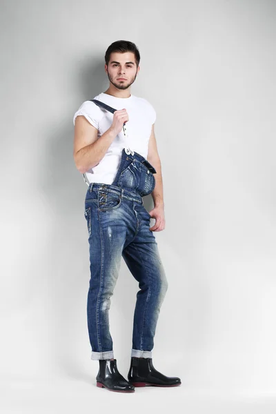 Homem de macacão jeans em fundo cinza — Fotografia de Stock