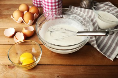 Hazırlık ahşap arka plan üzerinde cam kasede yumurta ile krem