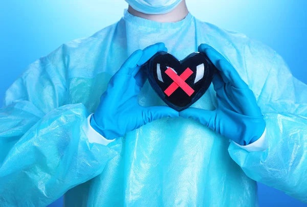 Доктор тримає декоративне серце на синьому фоні — стокове фото