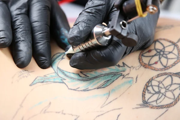 Tattooer showing process of making tattoo, close up — Stock Photo, Image