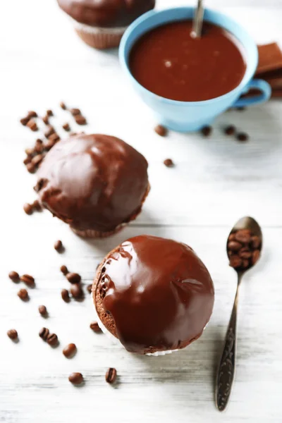 Muffins de chocolate caseiros saborosos e xícara de café na mesa de madeira — Fotografia de Stock