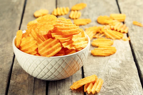 Delicious potato chips in bowl on wooden table close-up — Stock Photo, Image