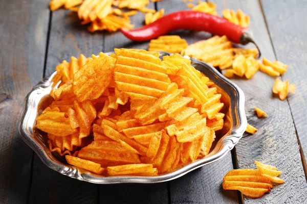 Delicious potato chips on plate on wooden table close-up — Stock Photo, Image