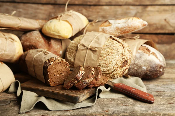 Different fresh bread, on old wooden table — Stock Photo, Image