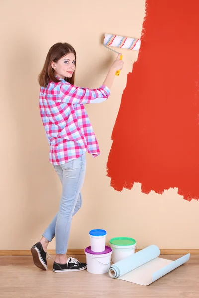 Hermosa mujer pinta la pared en la habitación — Foto de Stock