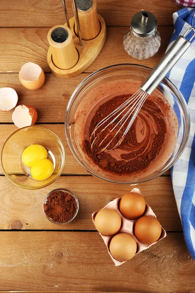 Zubereitungscreme mit Eiern und Kakao in Glasschale auf Holzgrund — Stockfoto