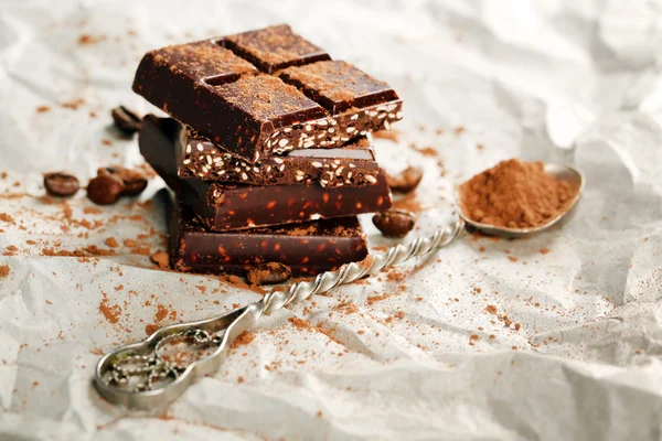 Stukken van chocolade met cacao op perkament, close-up — Stockfoto