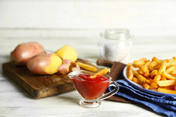 Smakelijke Franse frietjes op plaat, op houten tafel achtergrond — Stockfoto