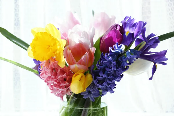 Bellissimo bouquet di fiori primaverili in vaso di vetro su sfondo tenda — Foto Stock