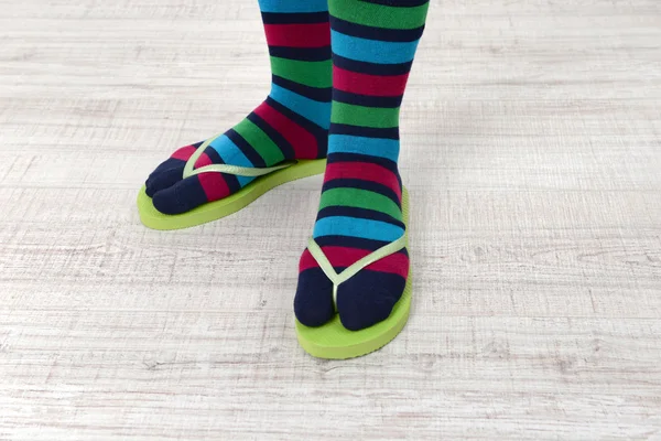 Female feet in socks with pink flip-flops, on floor background — Stock Photo, Image