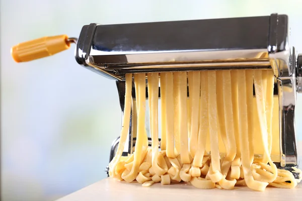 Making noodles with pasta machine on light background — Stock Photo, Image