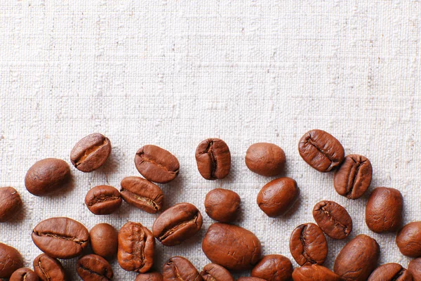 Frame of coffee beans on color sackcloth background — Stock Photo, Image