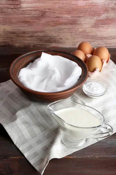 Brancos de ovo chicoteado e outros ingredientes para creme na mesa de madeira, close-up — Fotografia de Stock