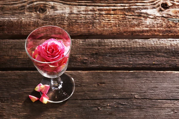 木製の背景にガラスの美しいピンクのバラ — ストック写真