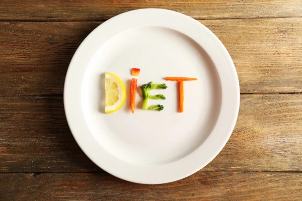 Słowo dieta wykonane w plasterkach warzywa w białe płytki na drewniane tła — Zdjęcie stockowe