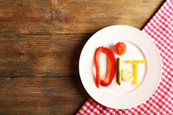 Słowo dieta wykonane w plasterkach warzywa w białe płytki na drewnianym stole, widok z góry — Zdjęcie stockowe