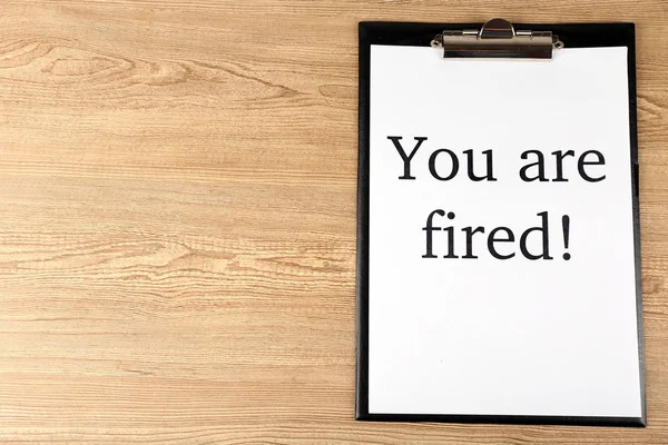Message You're Fired on clipboard on wooden table, top view — Stock Photo, Image