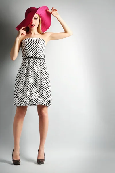 Expressieve jonge model in roze hoed op grijze achtergrond — Stockfoto