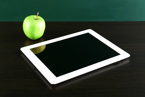 Tablet digital e maçã na mesa na frente do quadro-negro — Fotografia de Stock